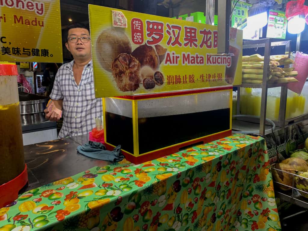 Man serving Air Mata Kucing in Jalan Alor Night Market in Kuala Lumpur Cheap Eats Food Tour