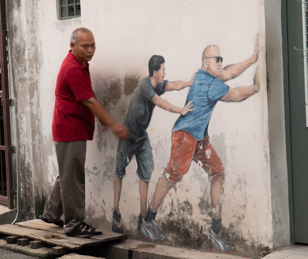 Man interacting with a mural in alley near Armenian Street