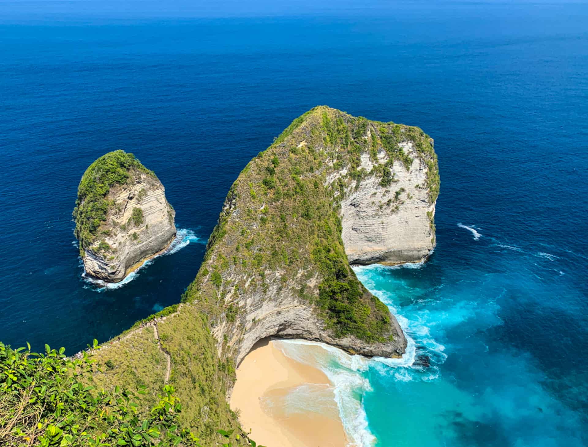 Overlooking Kelingking beach from high vantage point. Beautiful blue ocean and rock formation resembling a T-Rex dinosaur in Nusa Penida, Bali, Indonesia.